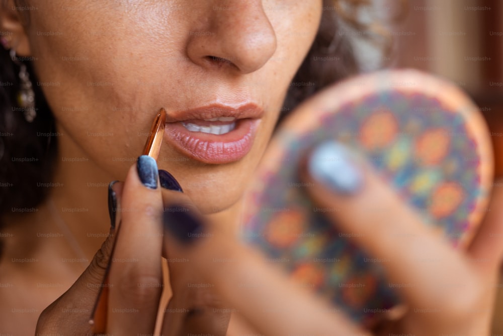 Eine Frau trägt mit einem Pinsel Lippenstift auf