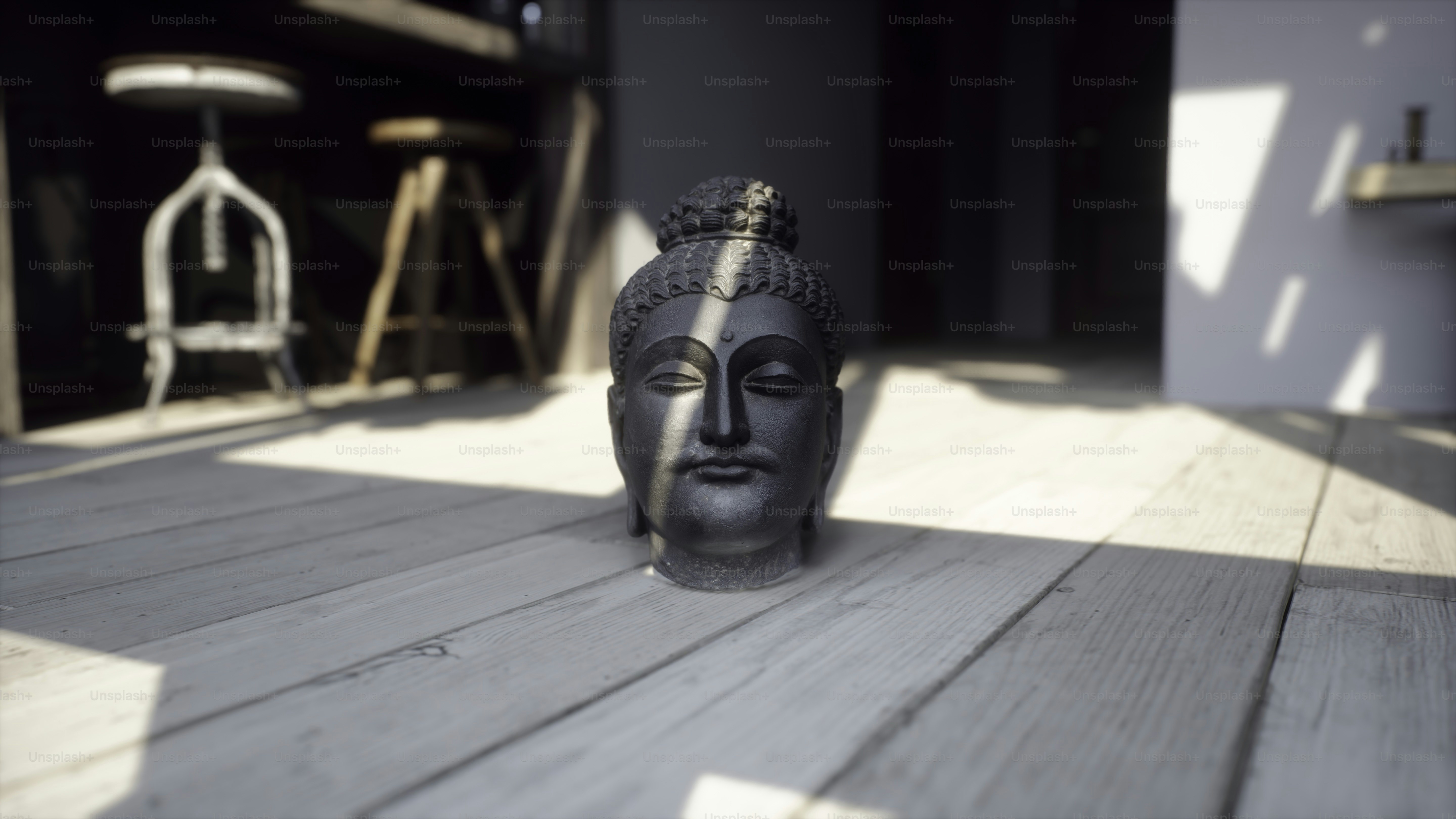 Eine Statue eines Buddha-Kopfes, der auf einem Holzboden sitzt