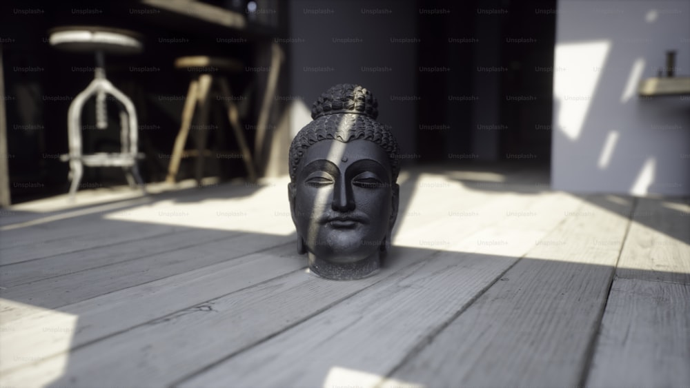 uma estátua de uma cabeça de buda sentada em um chão de madeira