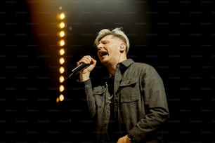 um homem cantando em um microfone no palco