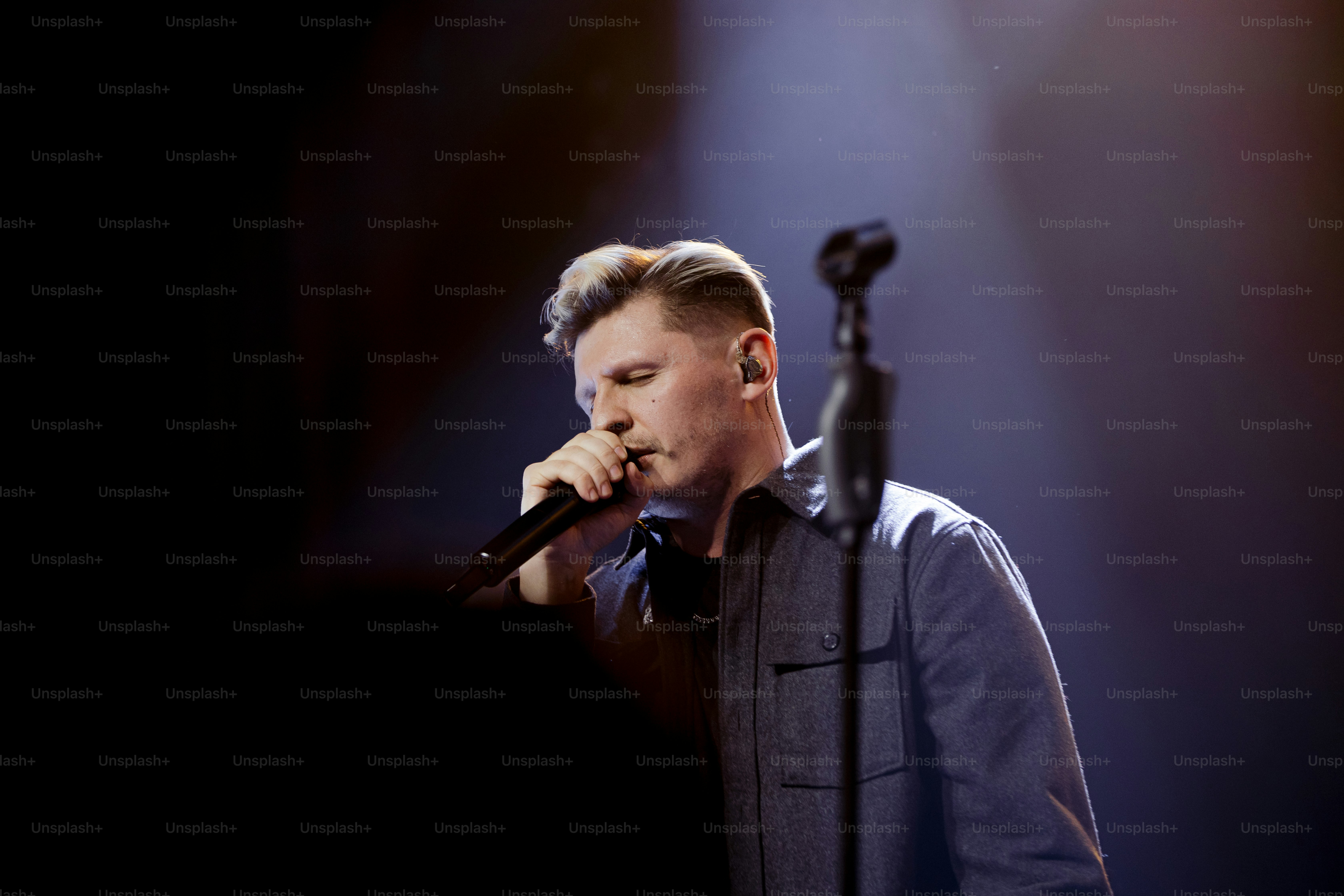 a man standing in front of a microphone on a stage