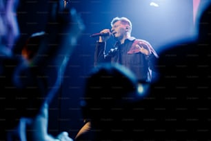 a man standing on top of a stage holding a microphone