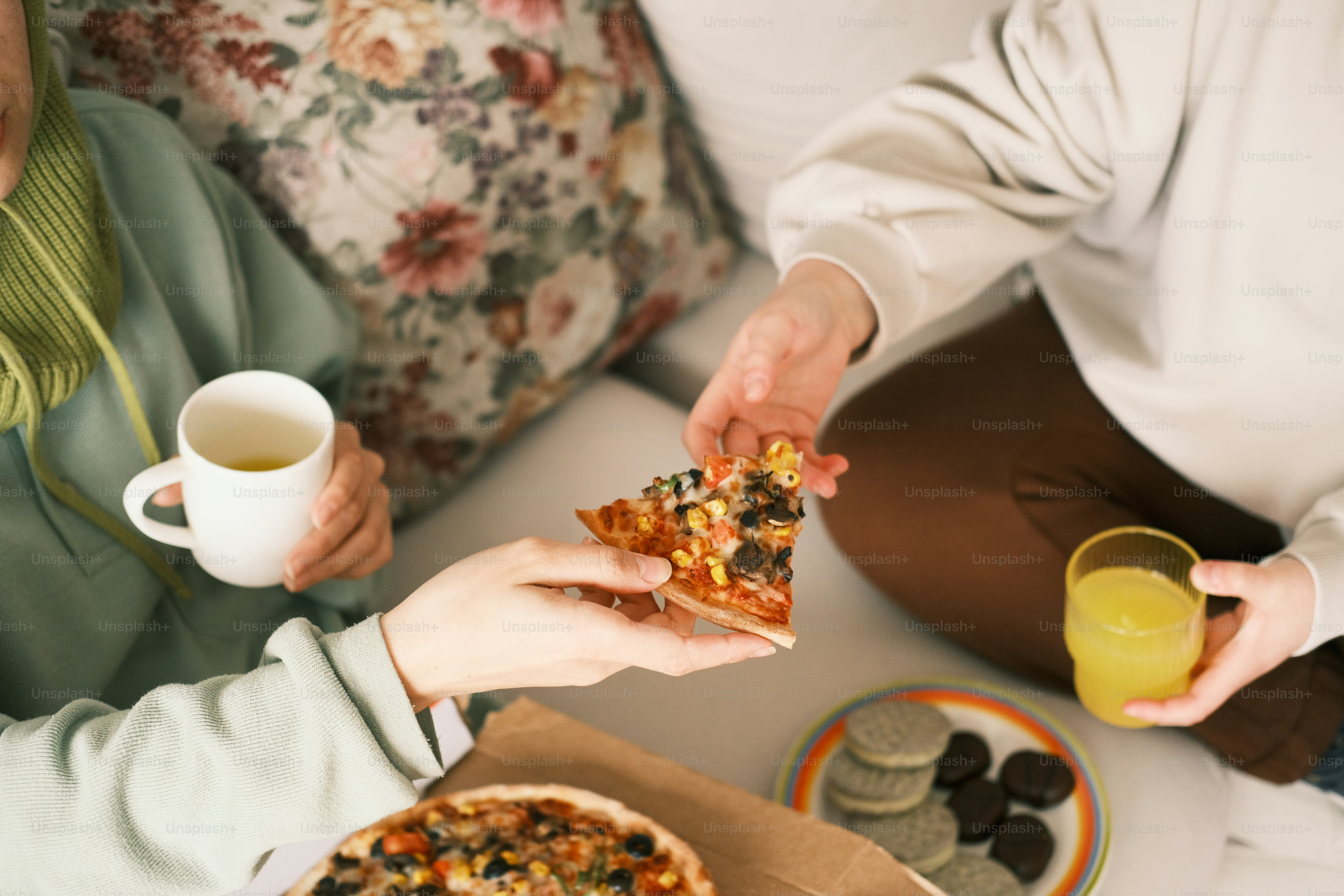 a couple of people sitting on a couch eating pizza