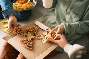 a person eating a slice of pizza from a box