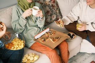 a group of people sitting on a couch eating pizza