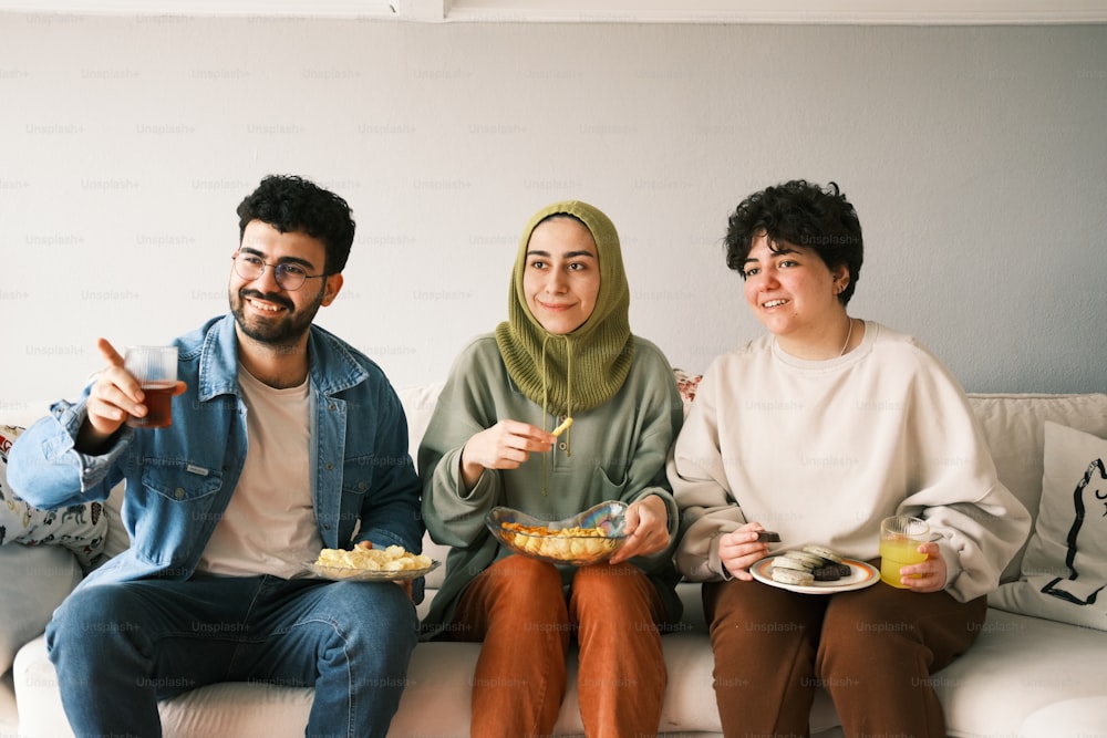 three people sitting on a couch eating food