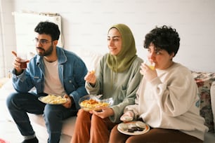 três pessoas sentadas em um sofá comendo comida