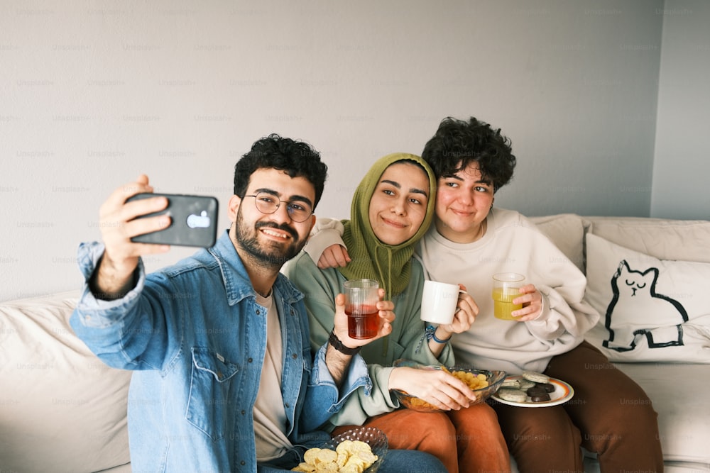 three people sitting on a couch taking a selfie