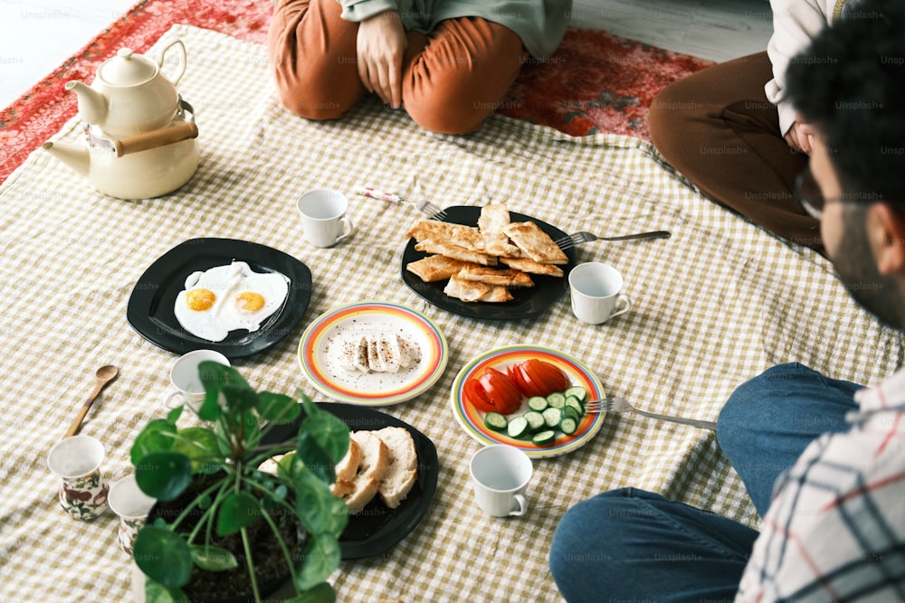 a man sitting on the floor with a plate of food in front of him