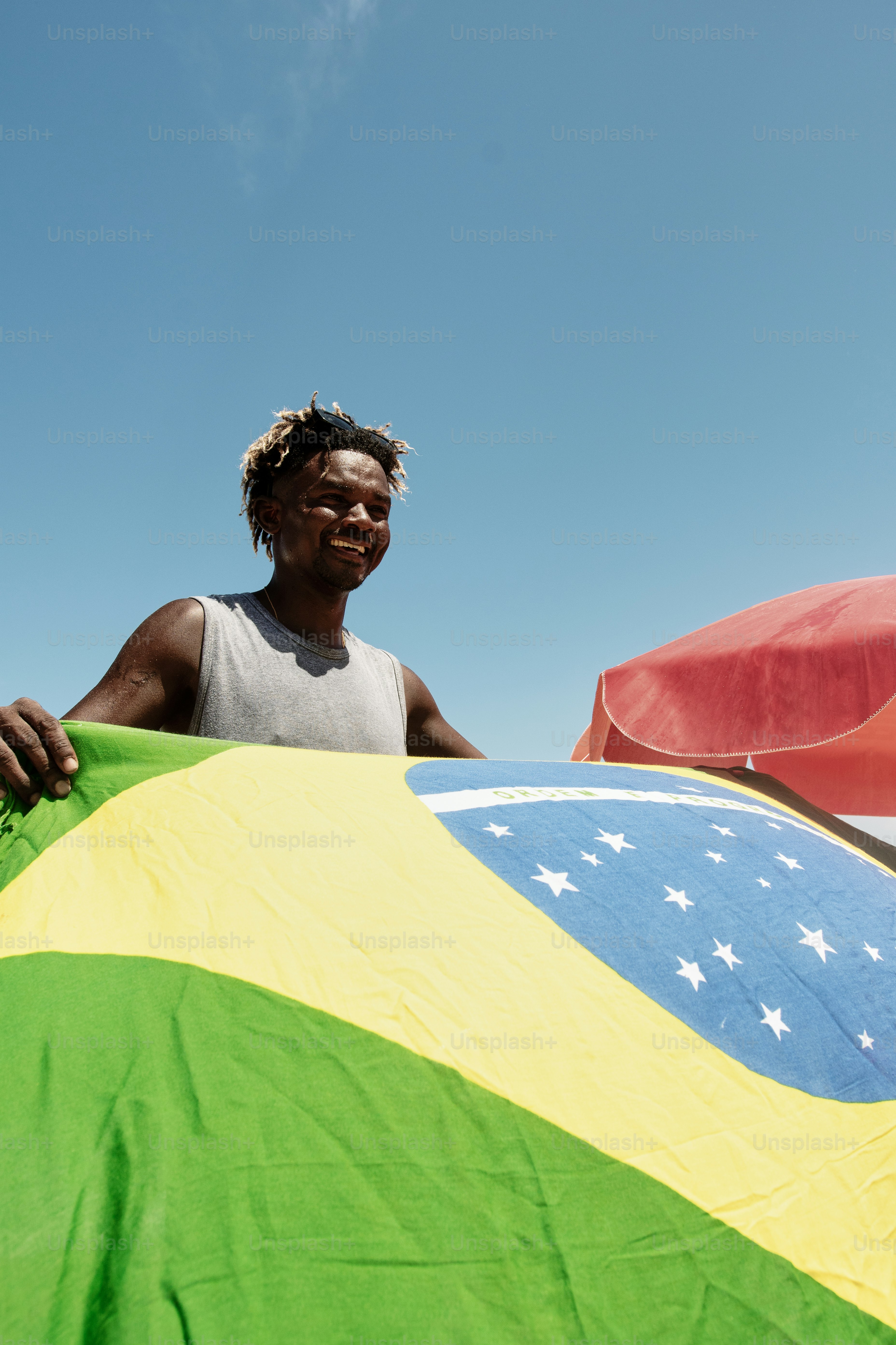 Un uomo che tiene una grande bandiera sotto un cielo blu