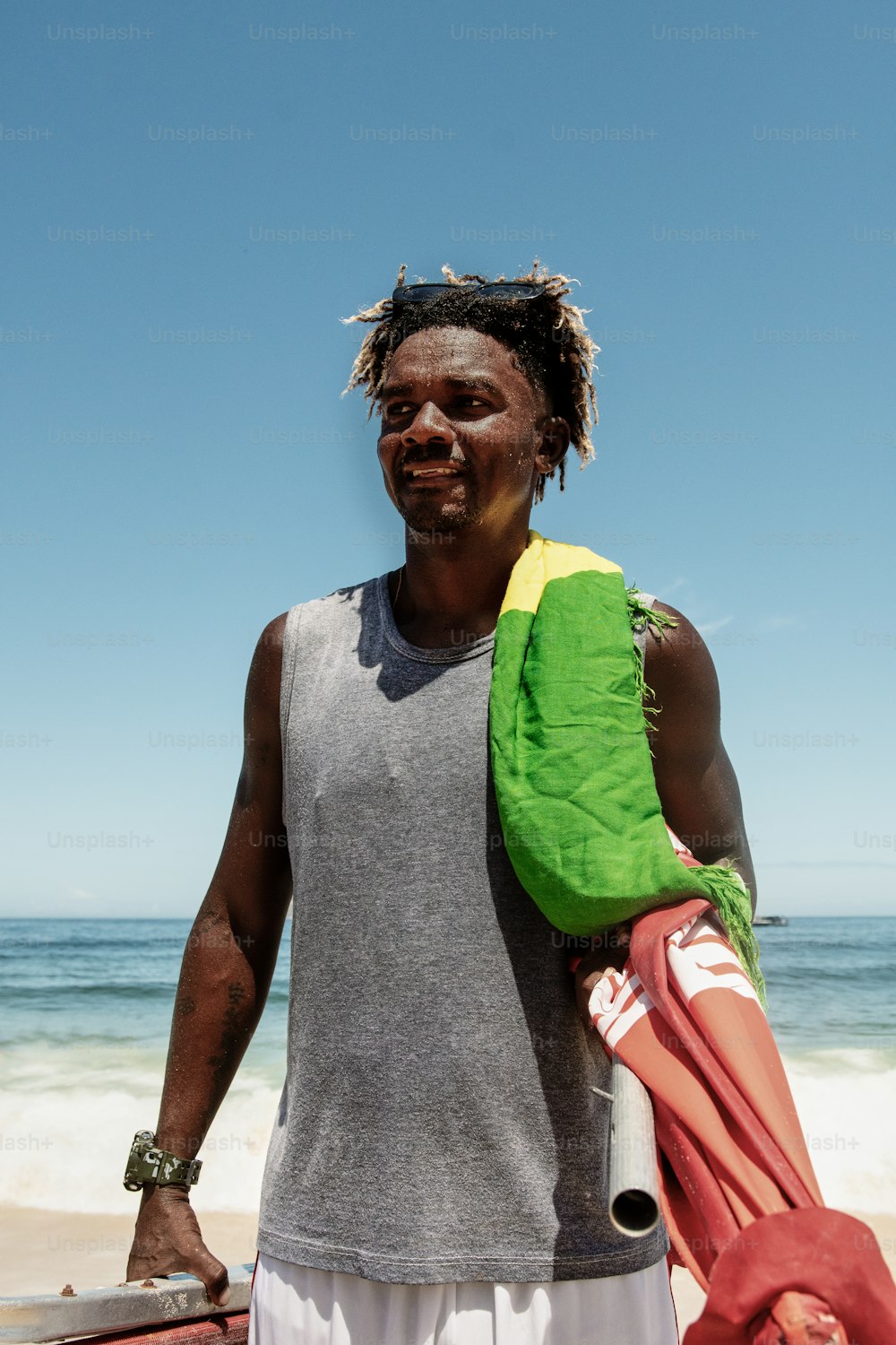 a man with dreadlocks holding a surfboard on the beach