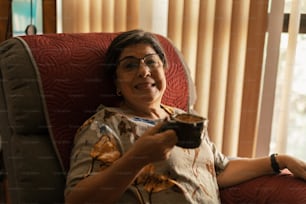 a woman sitting in a chair holding a cup of coffee