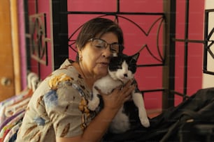 a woman holding a black and white cat in her arms