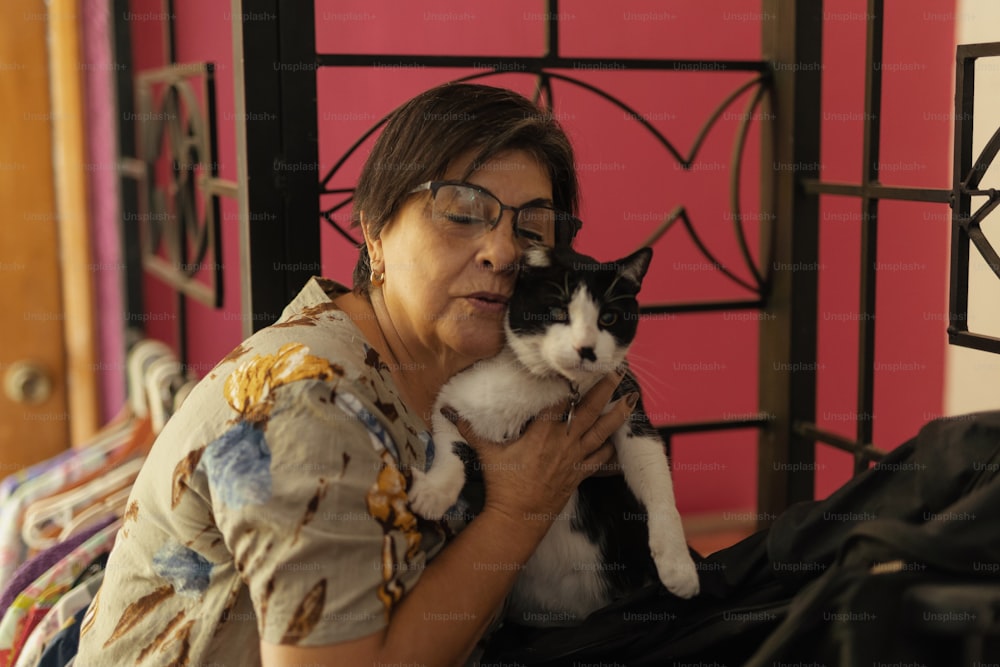 a woman holding a black and white cat in her arms