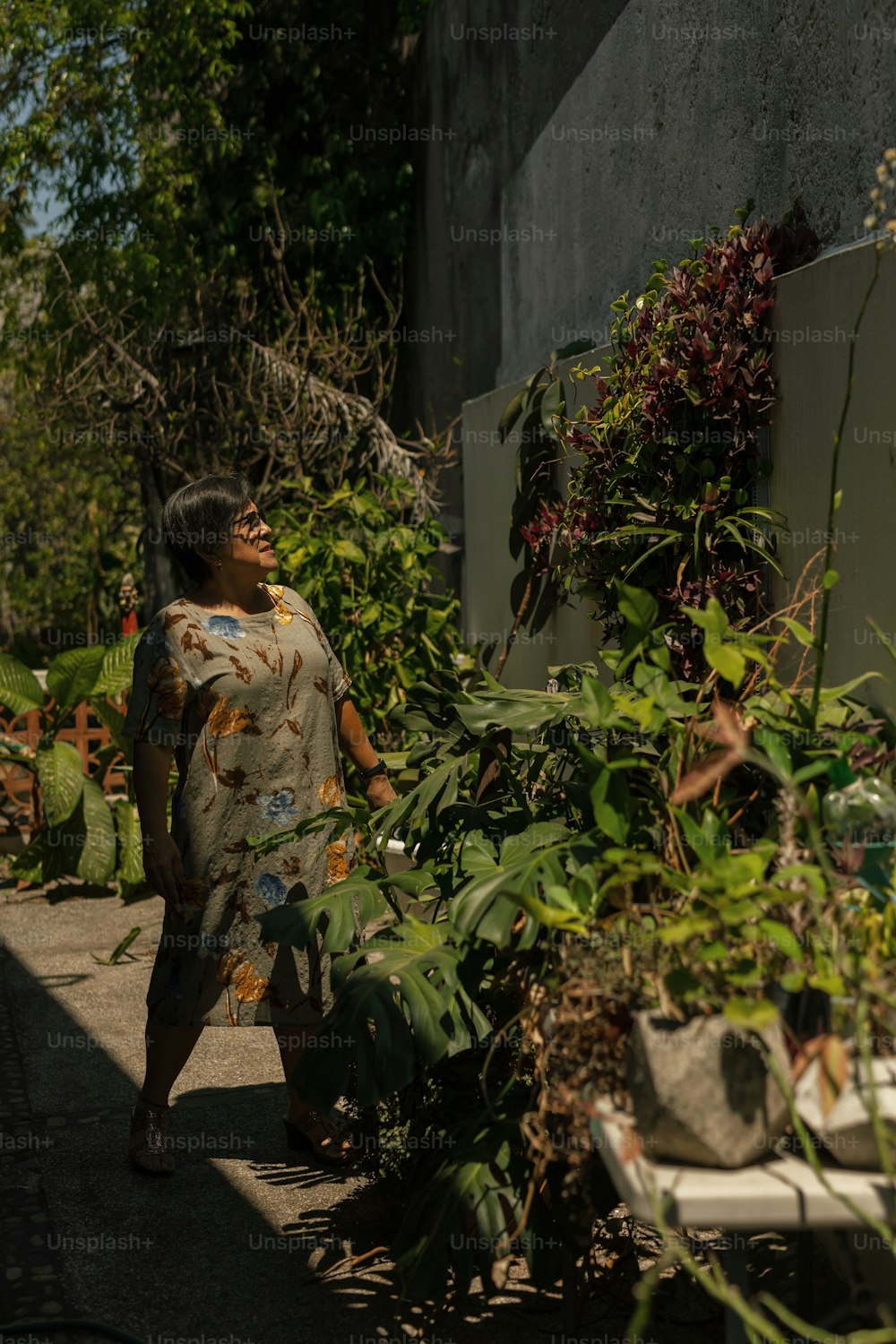a woman walking down a sidewalk next to a bunch of plants