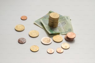 uma pilha de moedas sentada ao lado de uma pilha de dinheiro