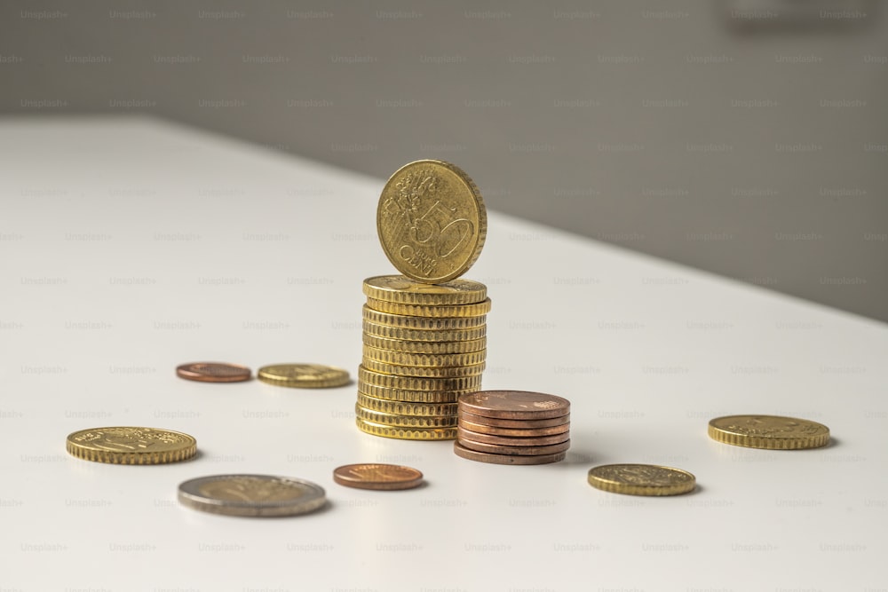una pila di monete seduta sopra un tavolo bianco