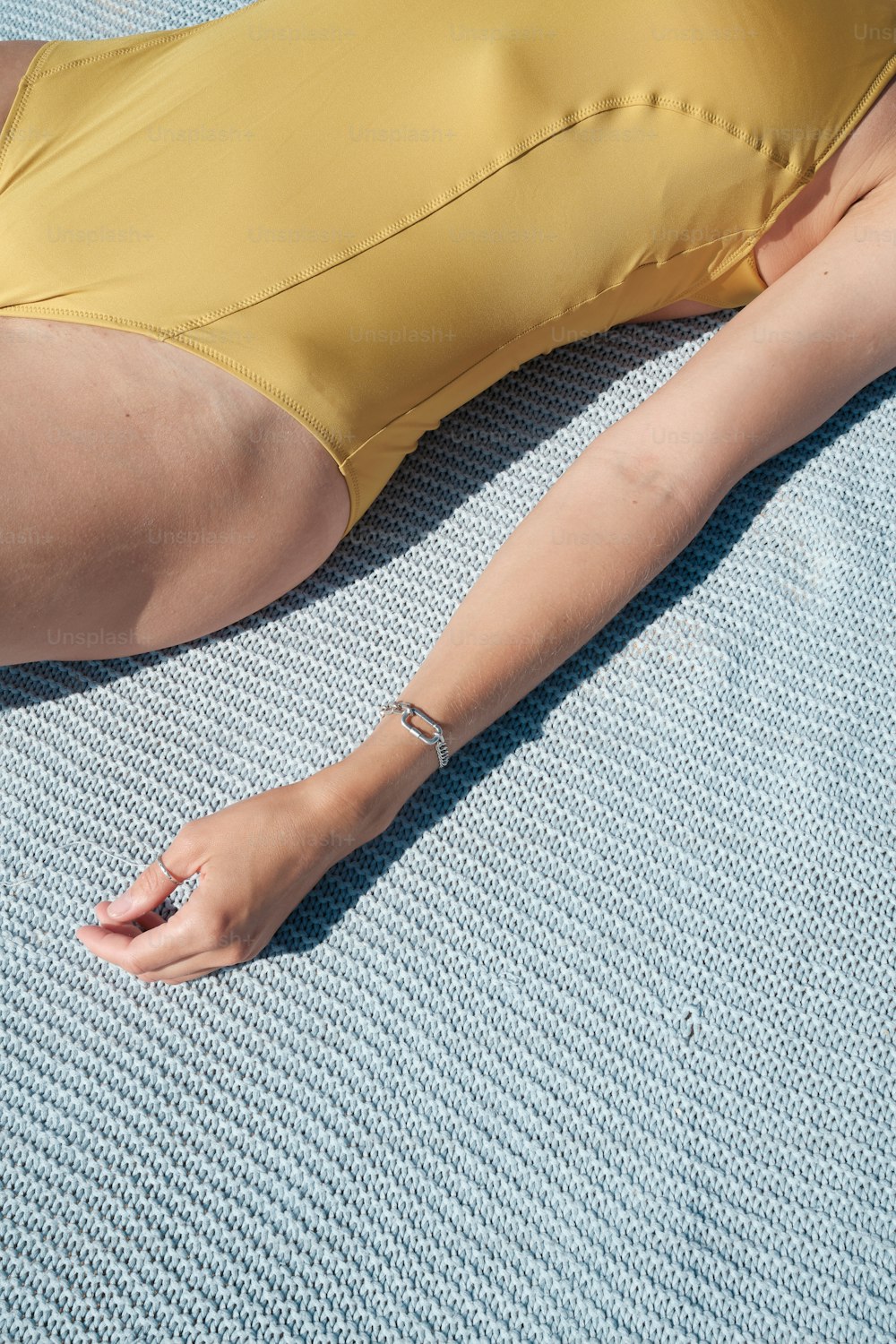a woman in a yellow swimsuit laying on a blue towel