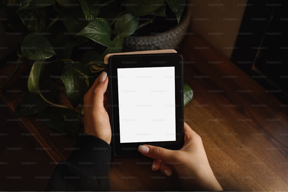 une personne tenant une tablette avec un écran blanc