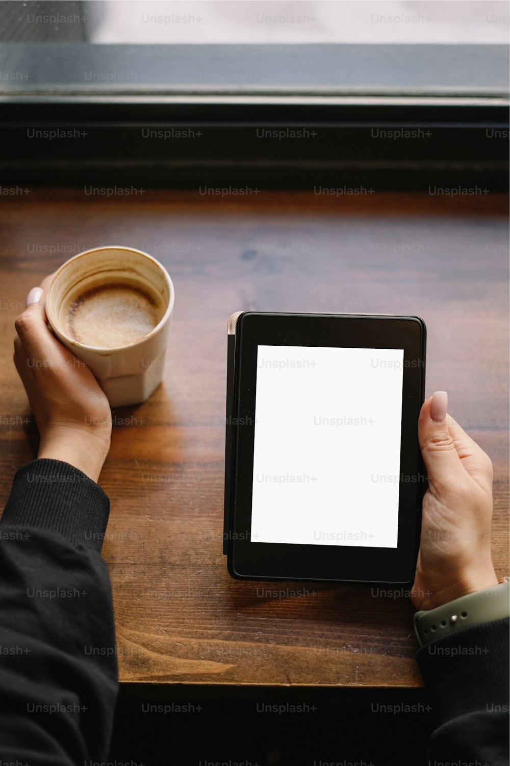 a person sitting at a table with a tablet and a cup of coffee