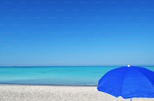 Una sombrilla azul sentada en la parte superior de una playa de arena