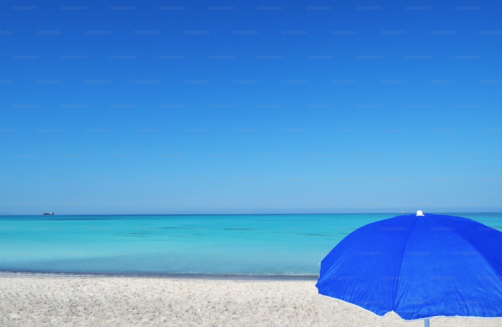 ein blauer Regenschirm auf einem Sandstrand