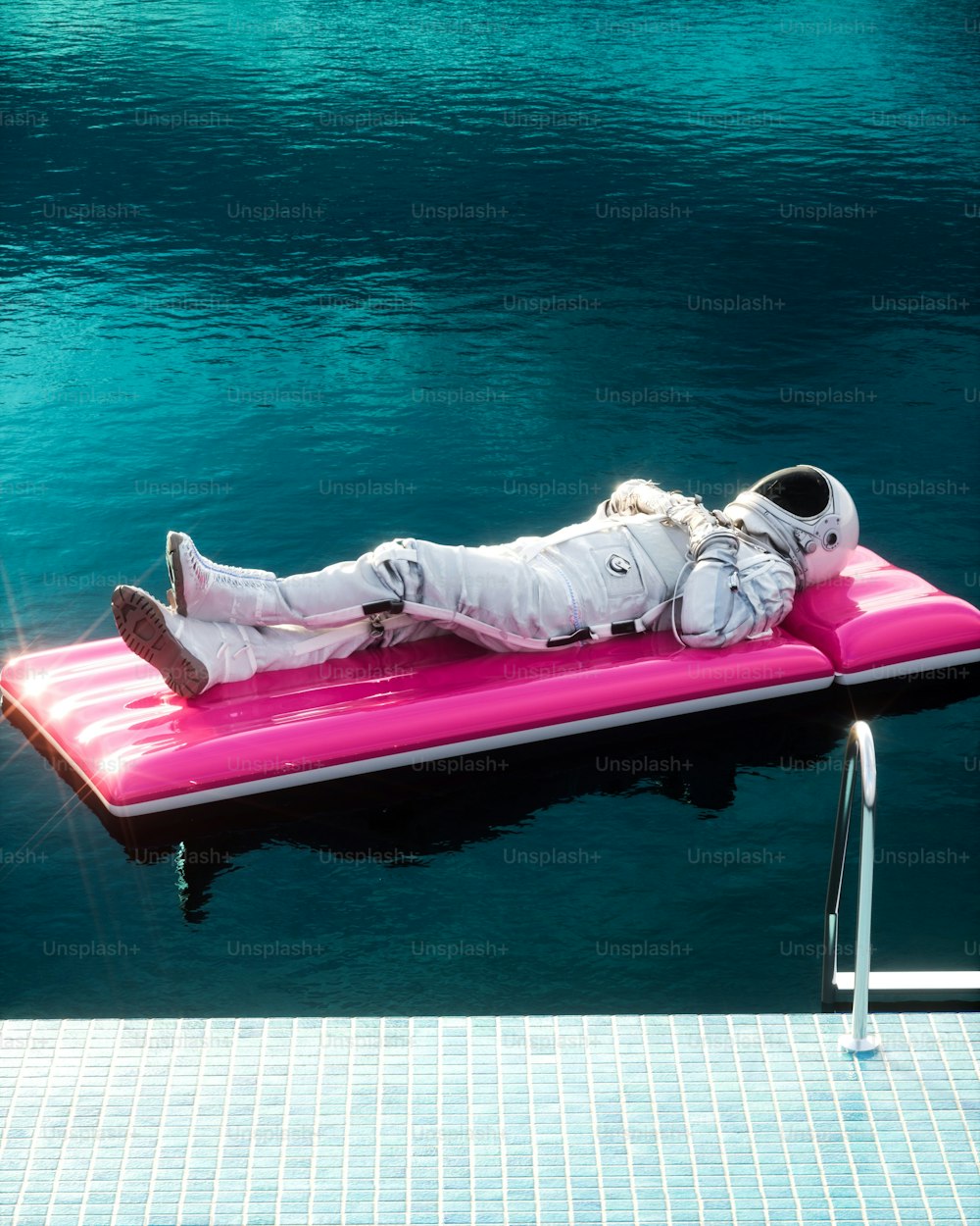 a man laying on top of a pink floater in the water