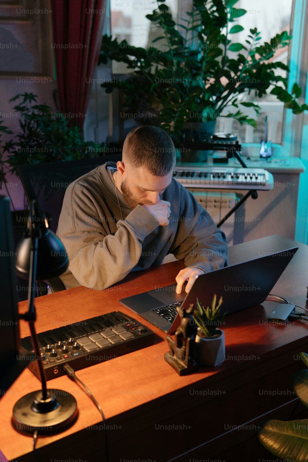 机に座ってノートパソコンで作業する男性