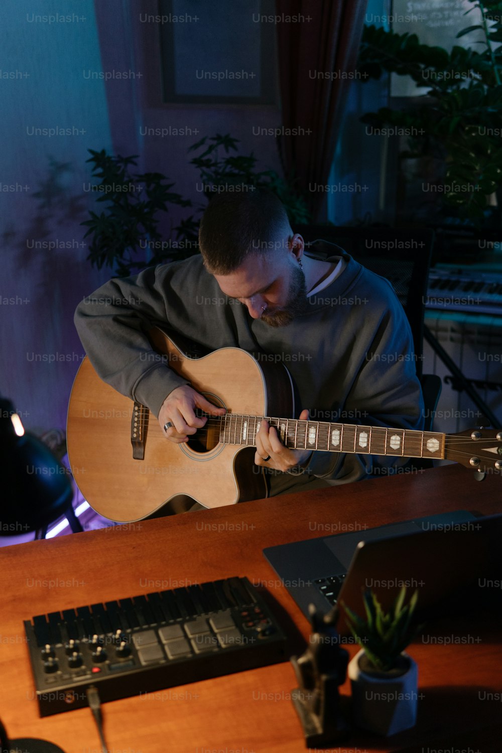 Un hombre sentado en un escritorio tocando una guitarra