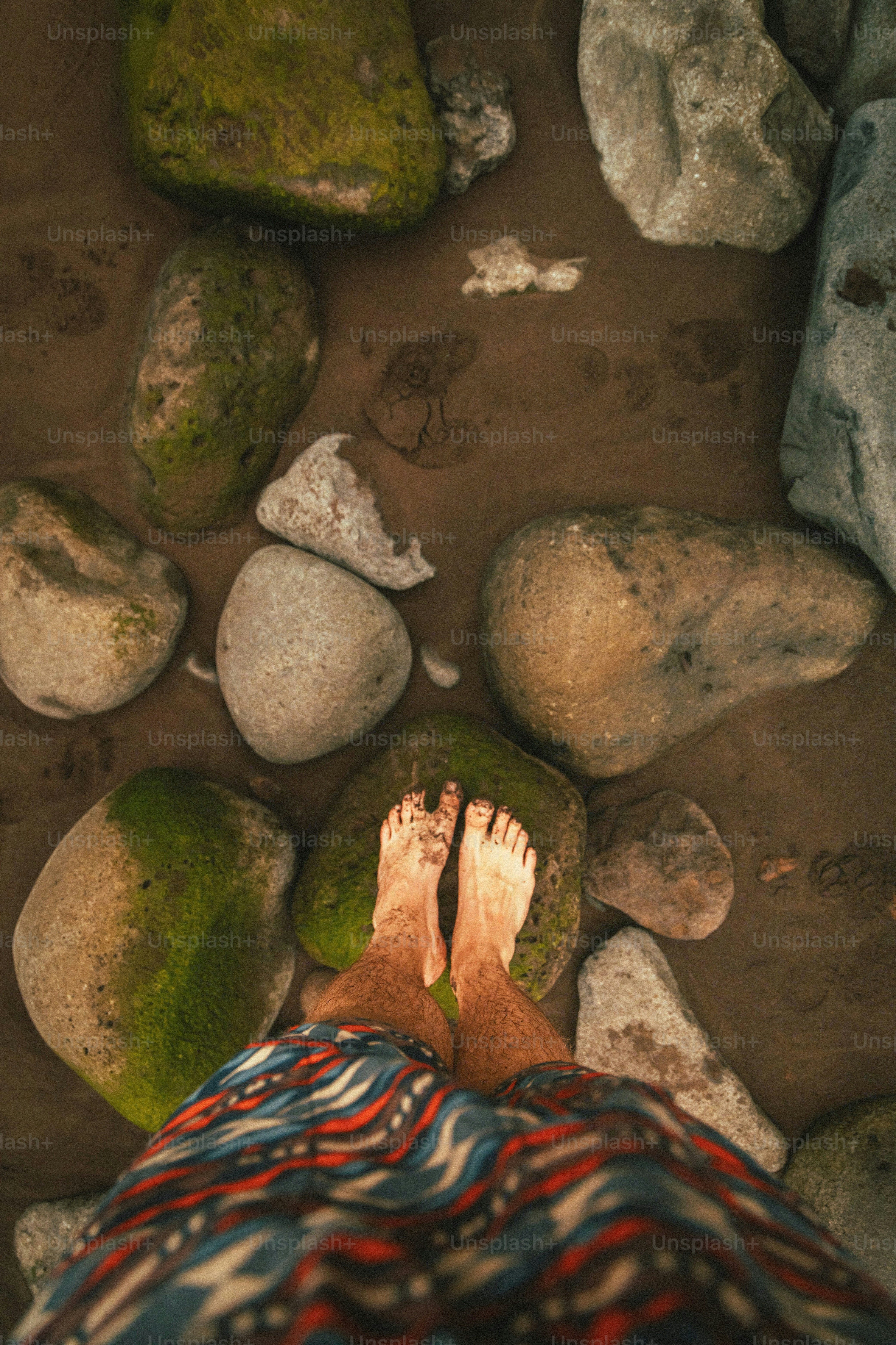 a person standing on a rocky beach next to rocks
