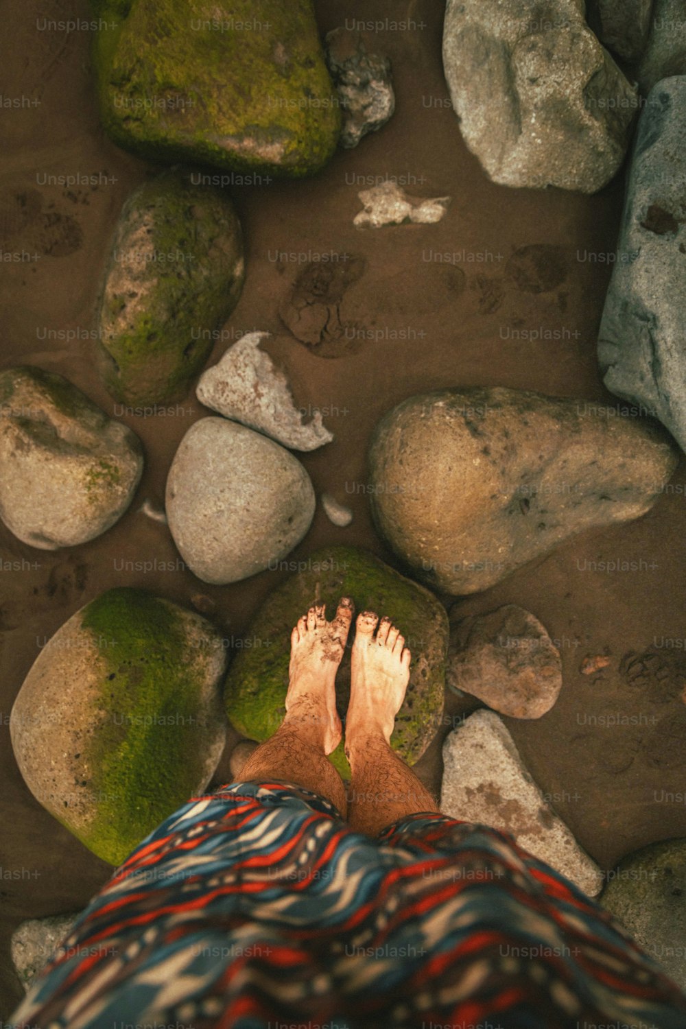 una persona in piedi su una spiaggia rocciosa vicino alle rocce