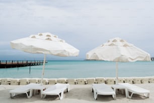two umbrellas and two lounge chairs on a beach