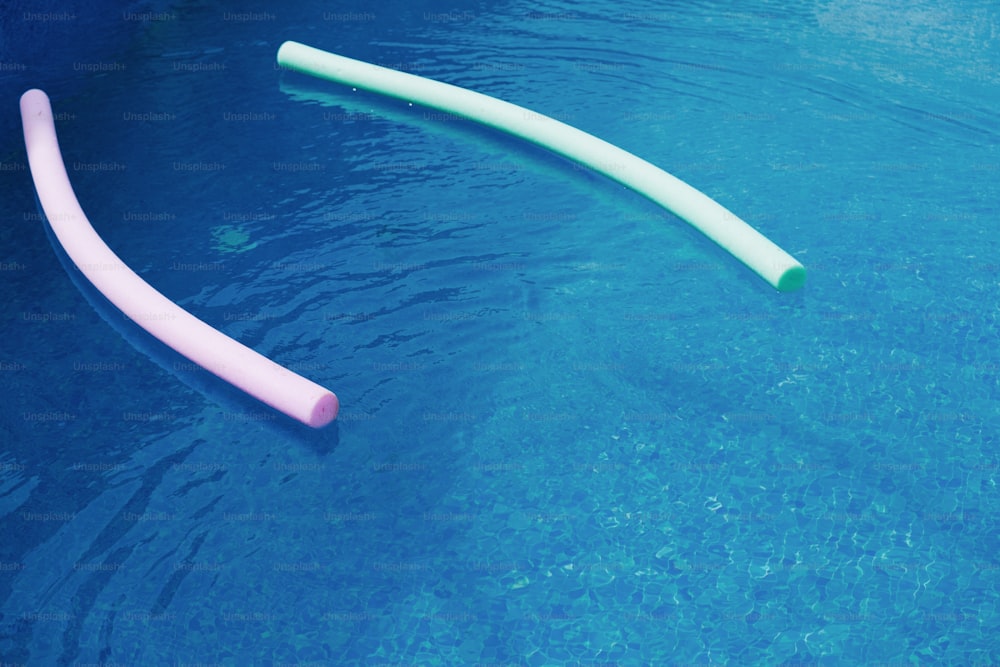 Un par de tubos rosados y blancos flotando en una piscina