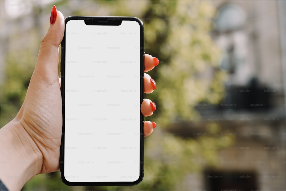La mano de una mujer sosteniendo un iPhone con una pantalla blanca