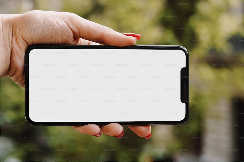 La mano de una mujer sosteniendo un teléfono celular con una pantalla en blanco