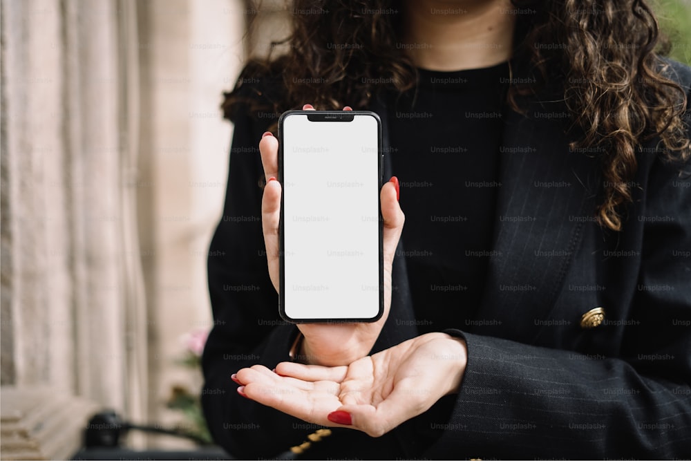 Una mujer sosteniendo un teléfono inteligente en sus manos