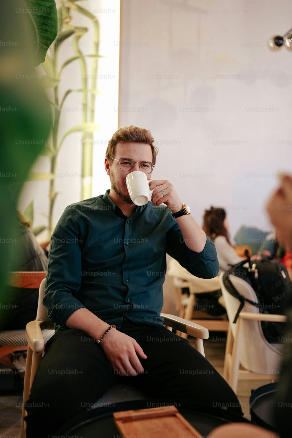 a man sitting in a chair drinking a cup of coffee