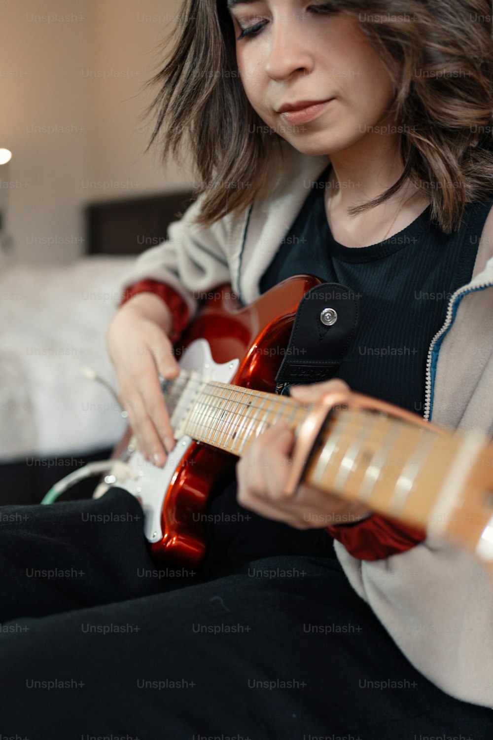 uma mulher sentada em uma cama tocando uma guitarra