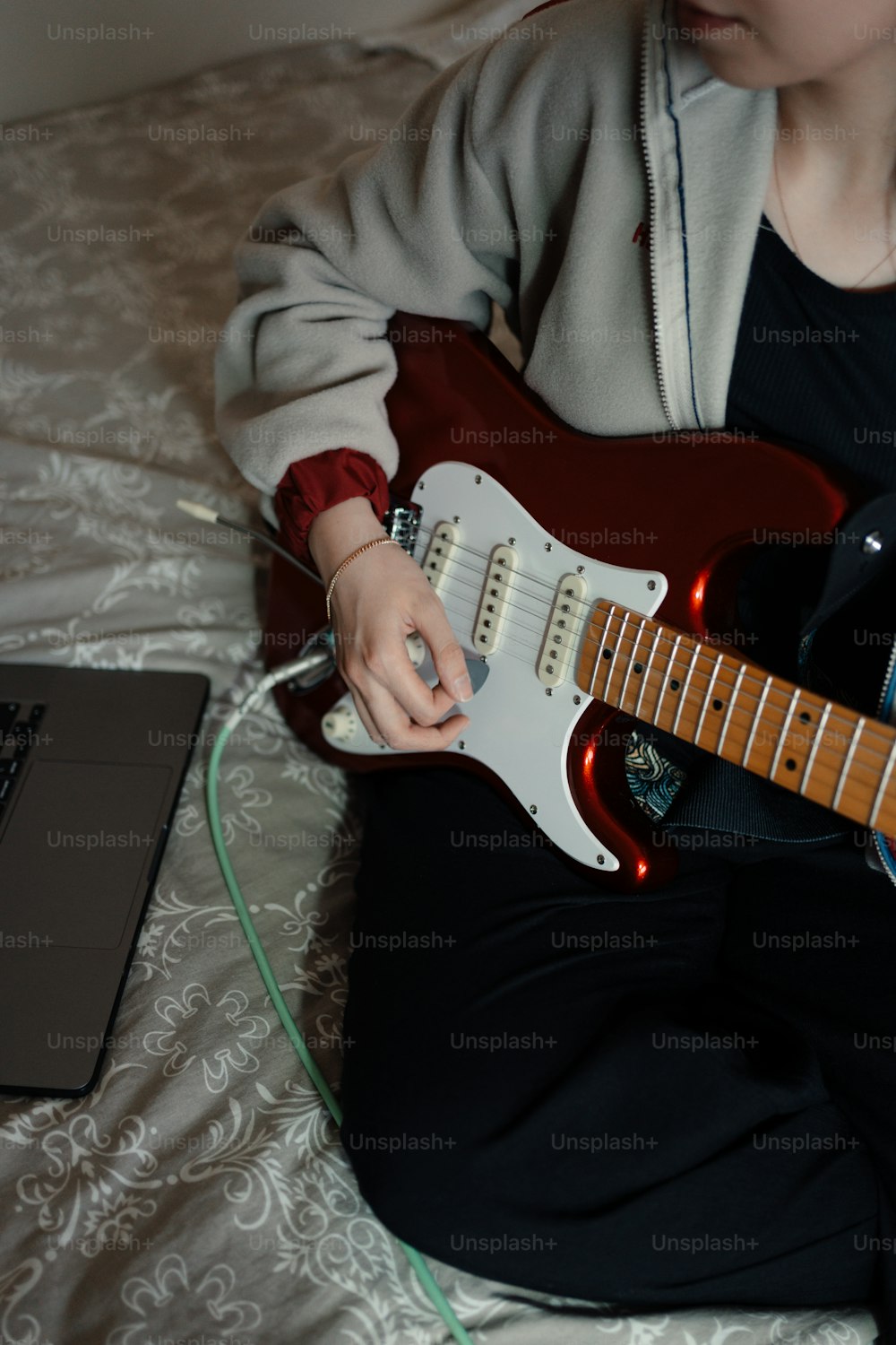 a person sitting on a bed playing a guitar