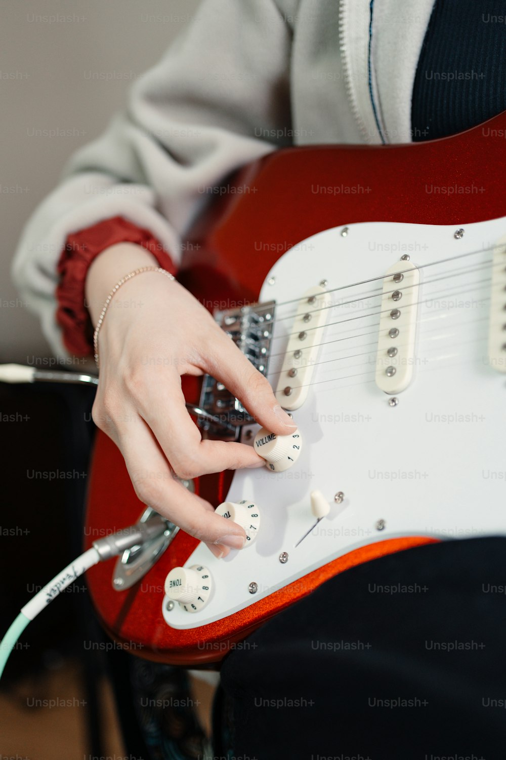 uma pessoa segurando uma guitarra elétrica vermelha e branca