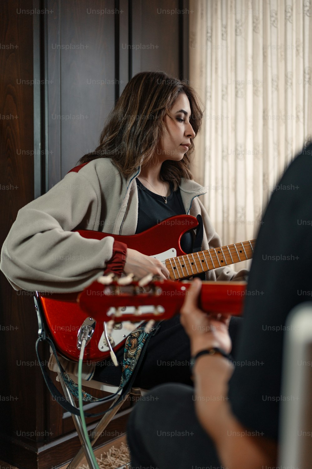 a woman sitting in a chair playing a red guitar
