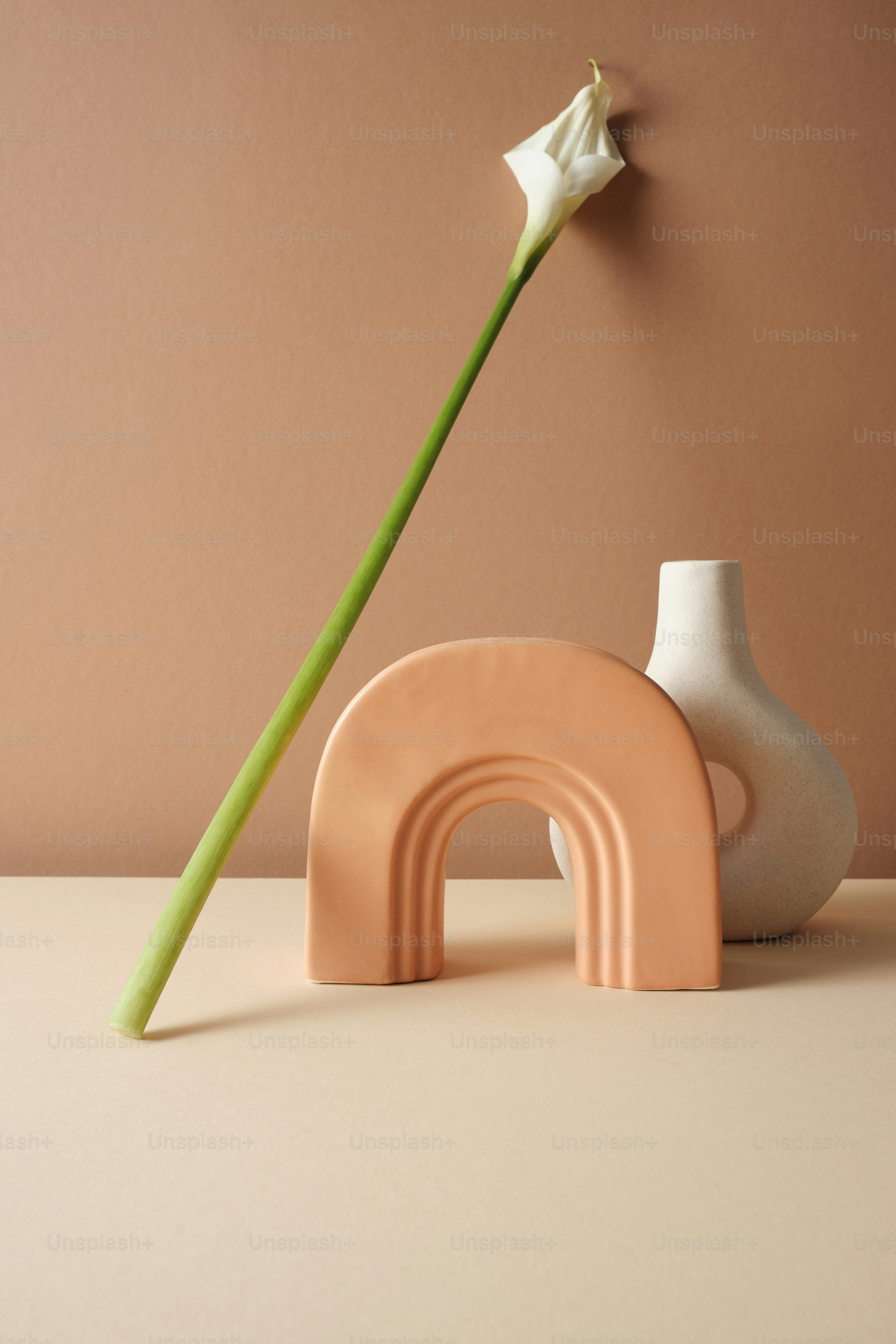 eine Vase mit einer Blume darin neben einer Skulptur