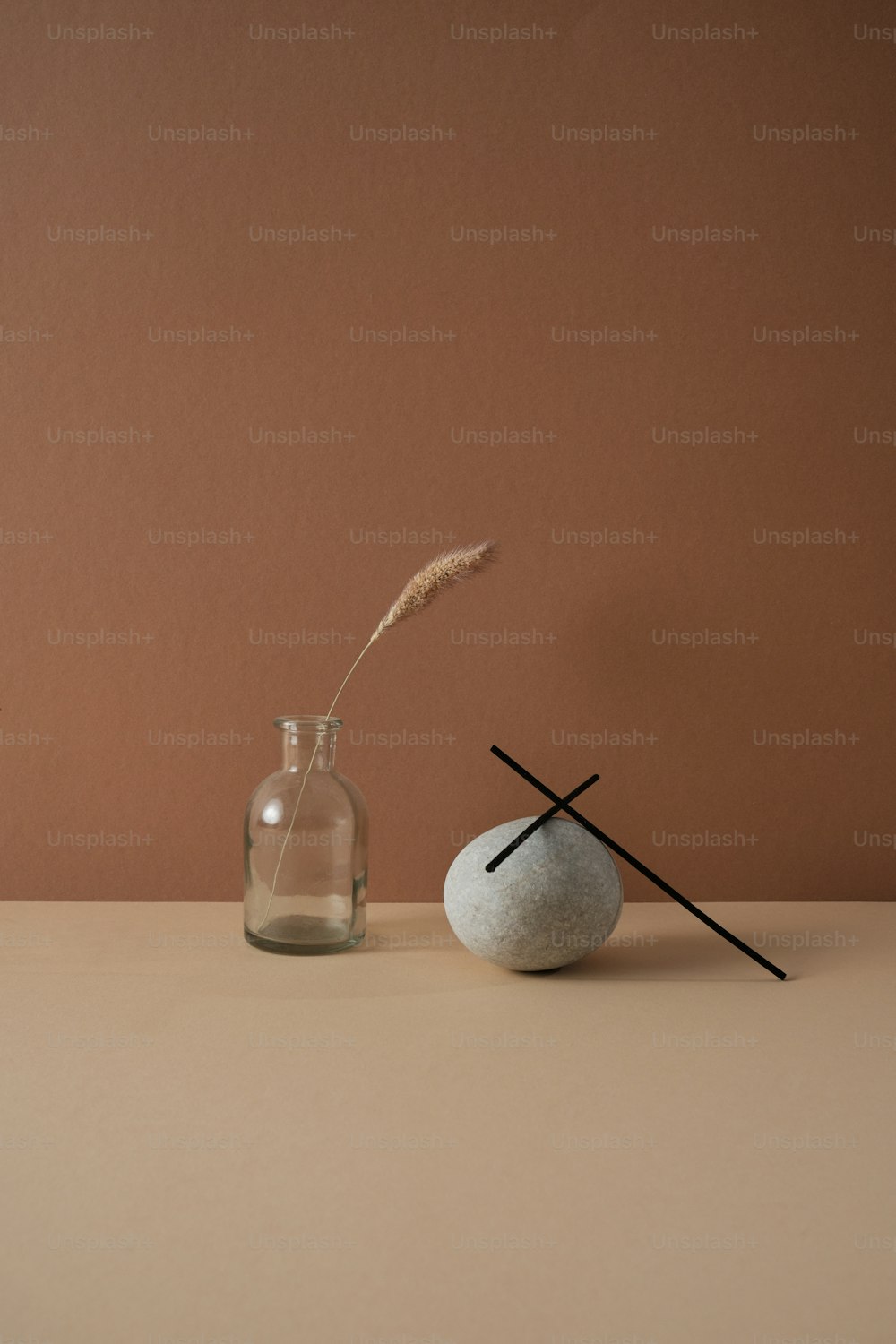 a vase with two sticks sticking out of it next to a rock