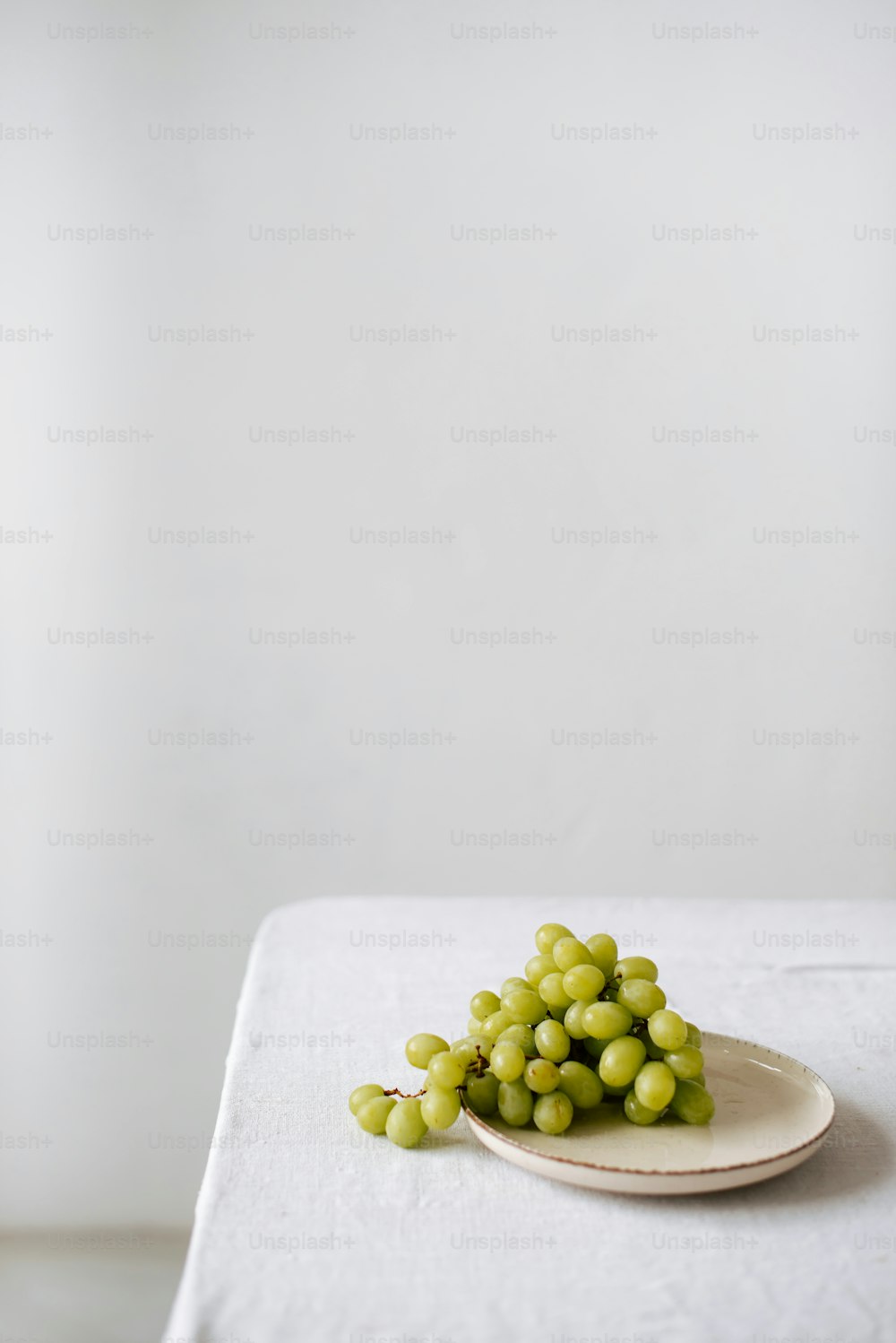 a plate of green grapes on a white table cloth