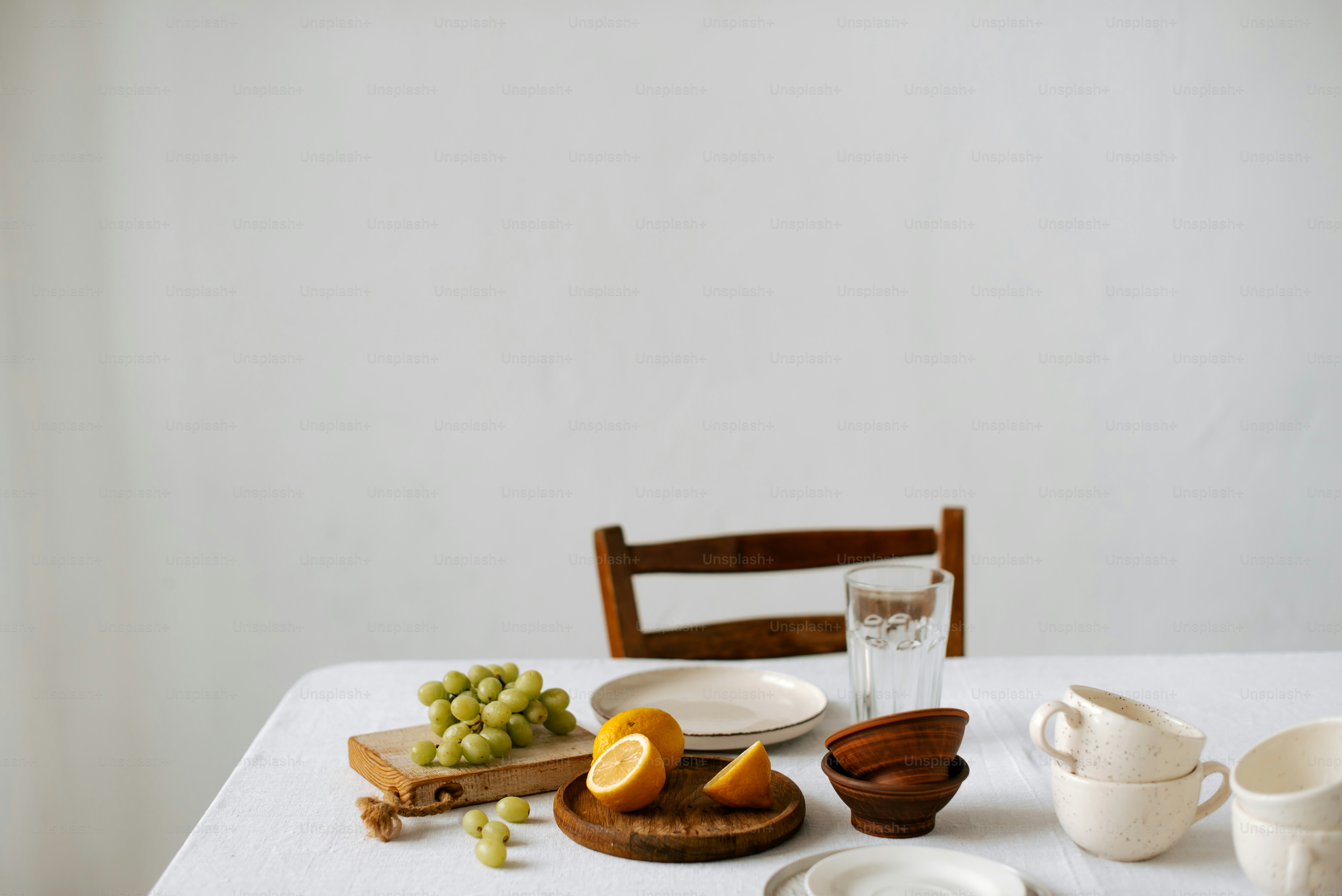 白いテーブルの上には、果物でいっぱいの皿とボウルが置かれています