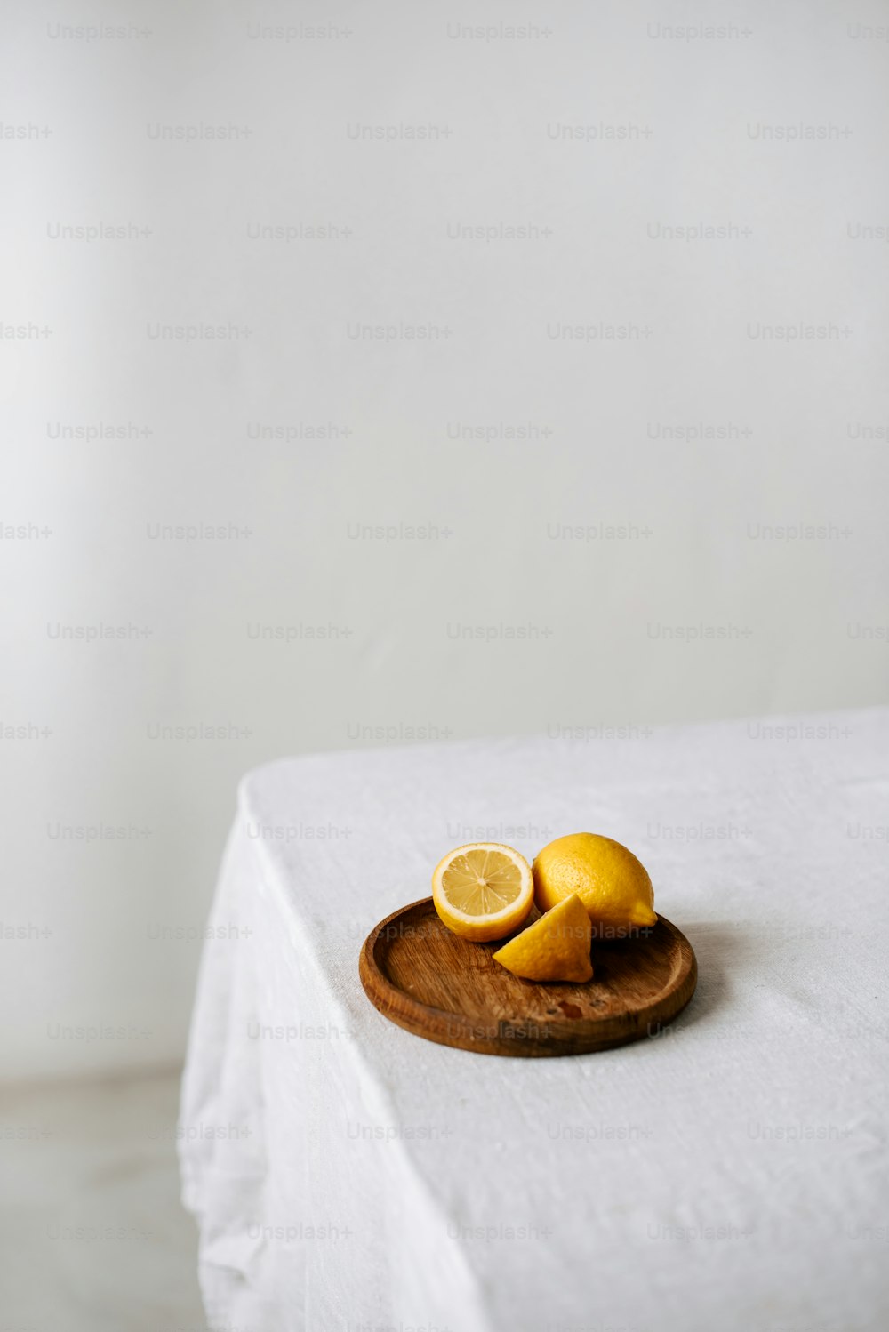 un piatto di legno sormontato da limoni affettati in cima a un tavolo