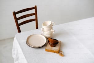 une table blanche surmontée d’assiettes et de tasses