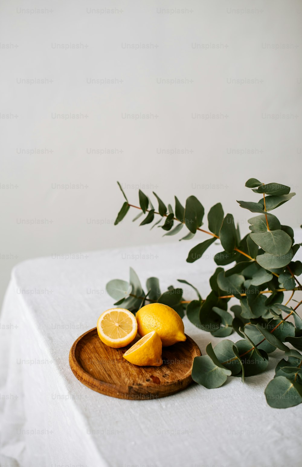 um prato de madeira coberto com limões fatiados ao lado de uma planta verde