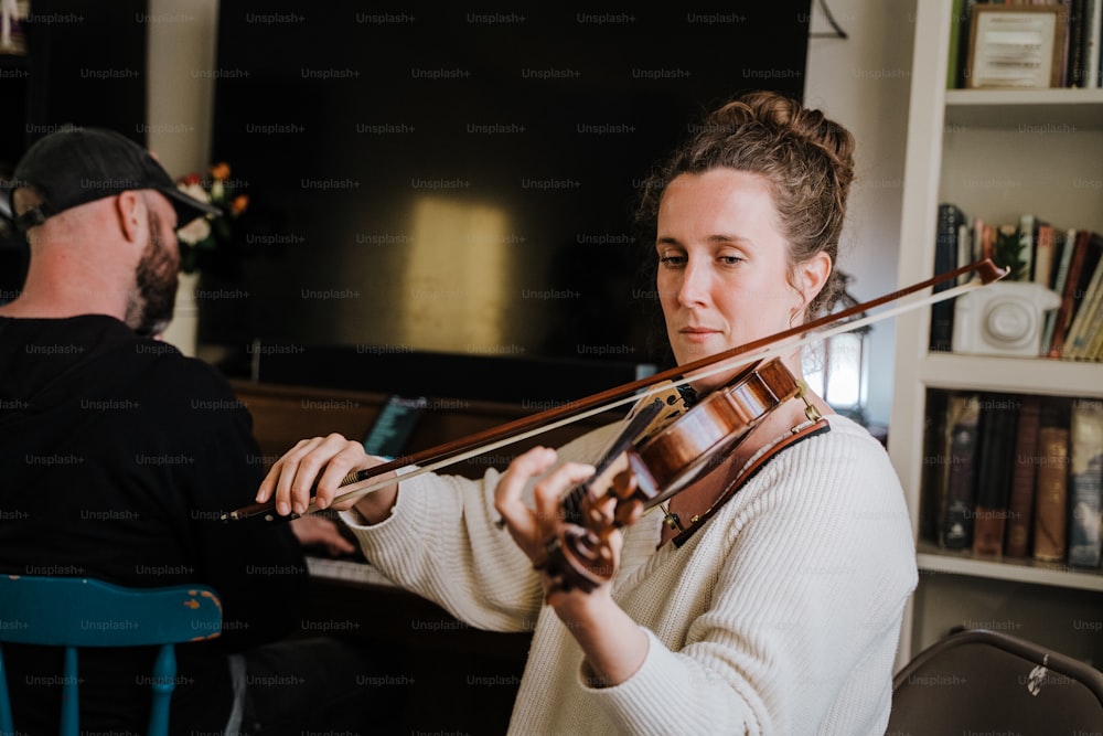 Un hombre y una mujer tocando el violín en una sala de estar