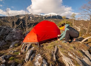 una donna che monta una tenda sulla cima di una montagna